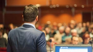 Back view of man speaking in front of audience