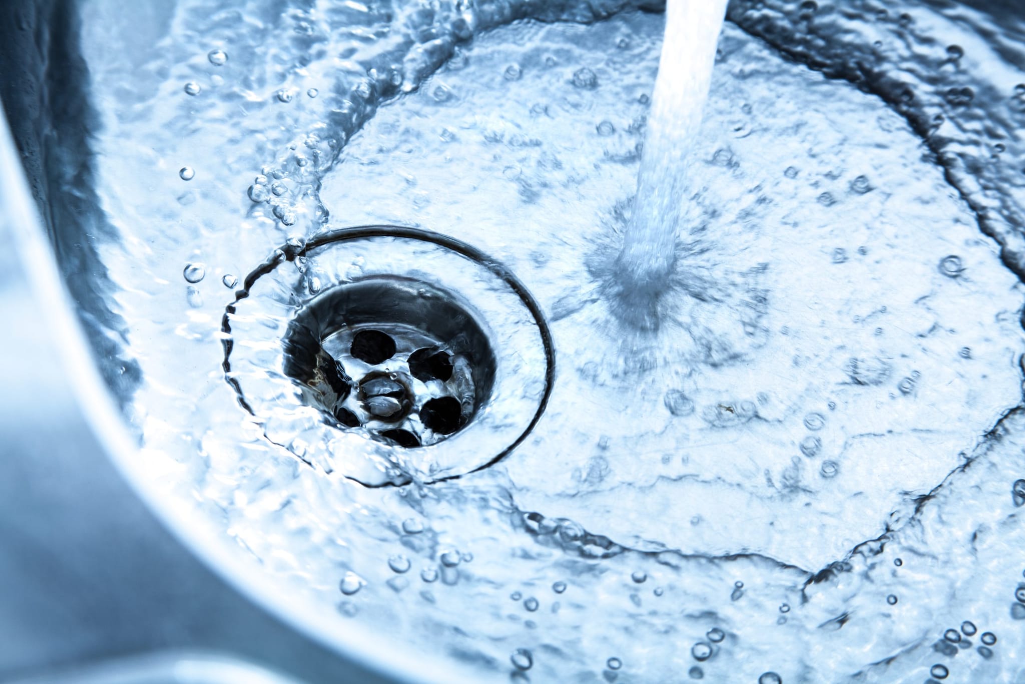 Water from faucet swirling down a drain