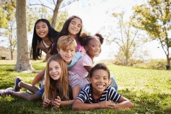 diverse group of children lying on each other in a park