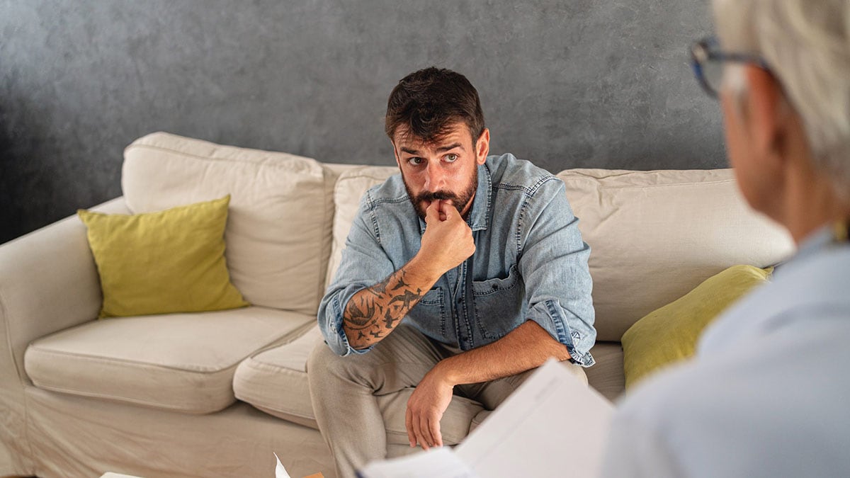 Concerned adult patient sitting on a couch talking with a doctor