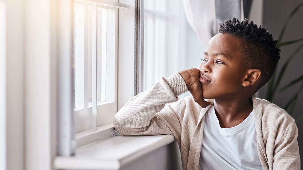 A young boy is looking out the window.