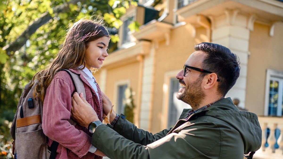 A father is saying goodbye to his daughter before she goes to school