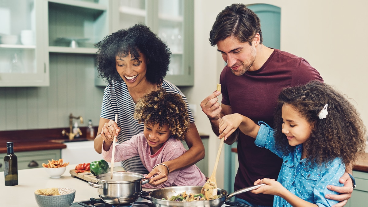 parents with their two daughters cooking food in the kitchen