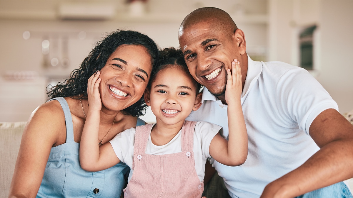 Two parents smiling with their daughter in between them