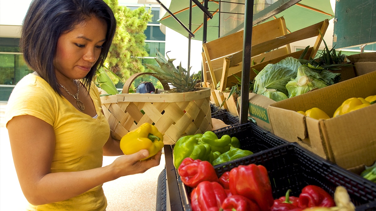 Woman standing in a farmer's market considering her purchase.