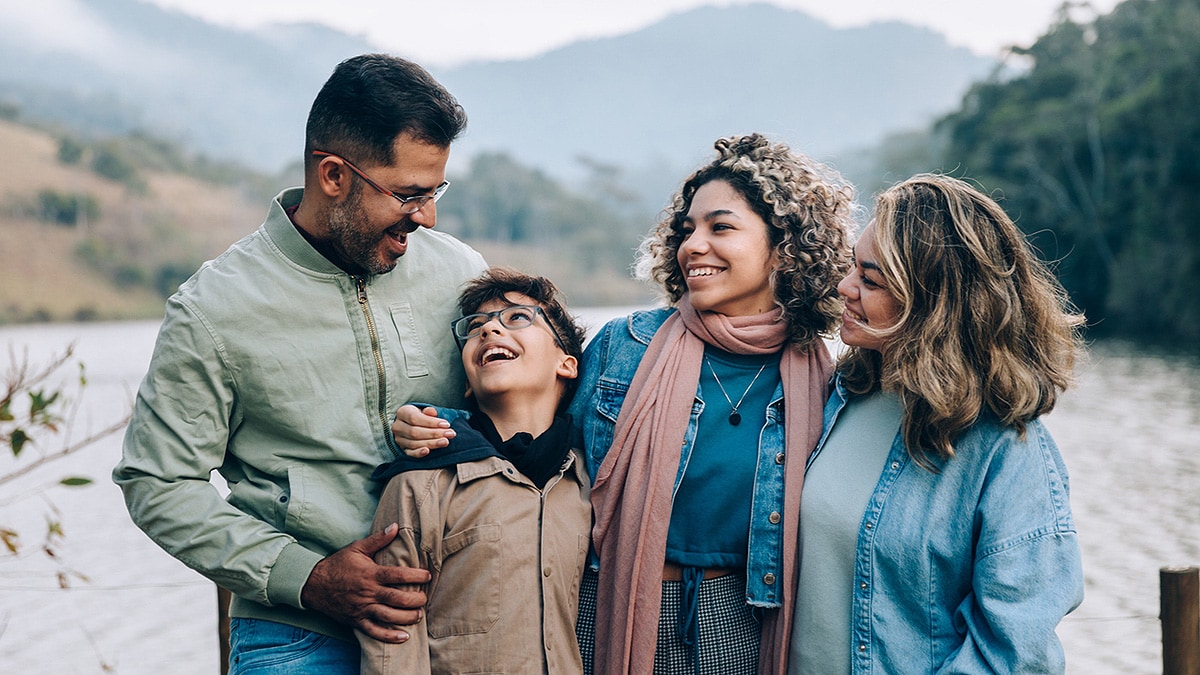 Family spending time outdoors in front of a lake and mountains.