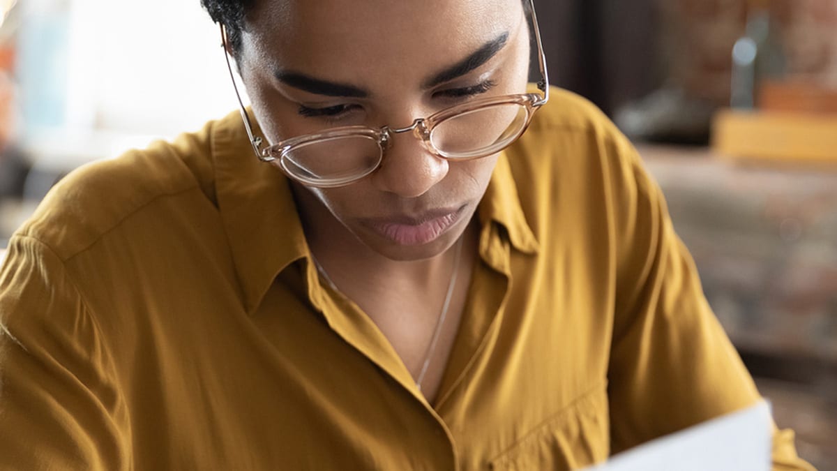 Person with glasses reading a paper.