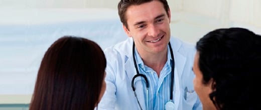 smiling doctor talking to couple