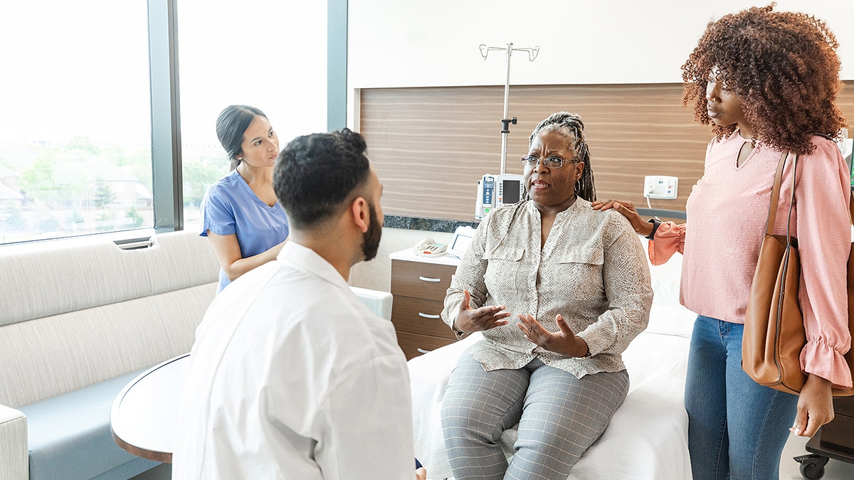 Woman talking with doctor with family present