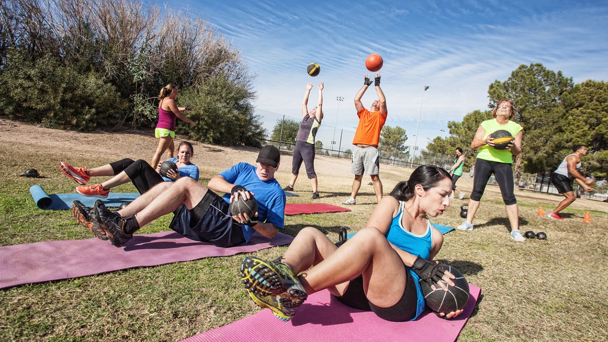 A group of teachers outdoors exercising and playing volleyball.