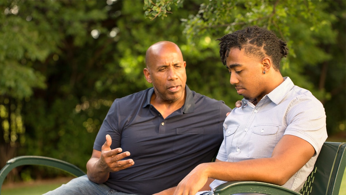 Father speaking with son on bench