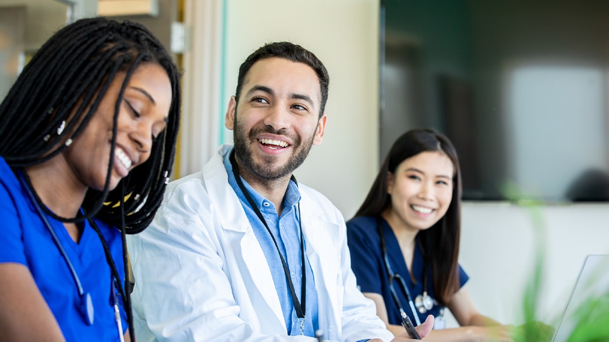 Tres médicos sentados en una mesa sonriendo.