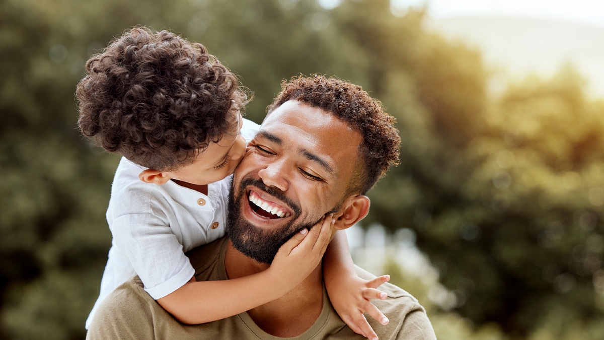 father with child on shoulders laughing