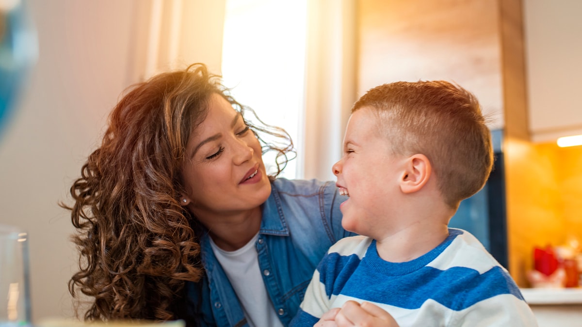 Madre ayudando a su hijo a hacer las tareas escolares en la cocina.