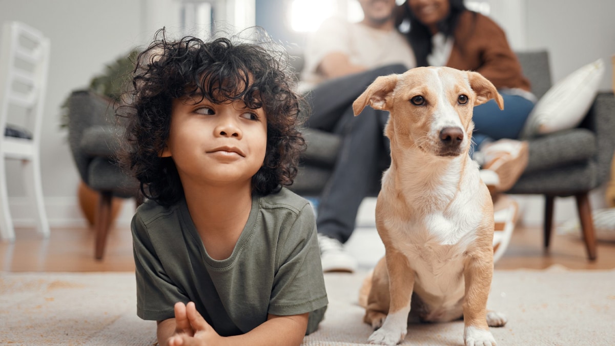 Boy and dog lying down on the floor and parents sitting on the couch