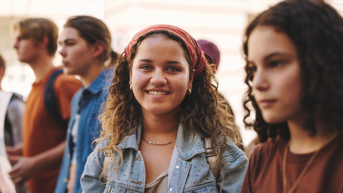 Happy teenage girl wearing bandana in the middle of other people