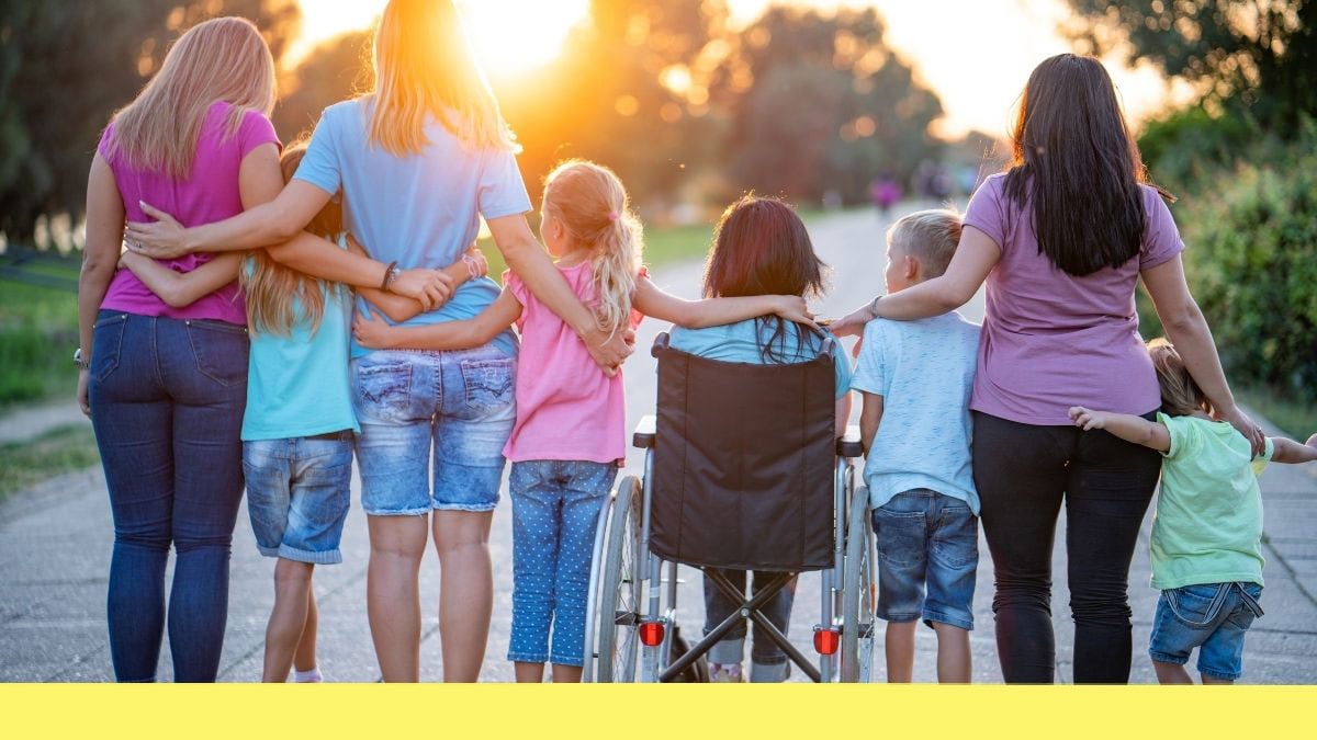 A group of children and caregivers with their arms around each other watching the sunset.