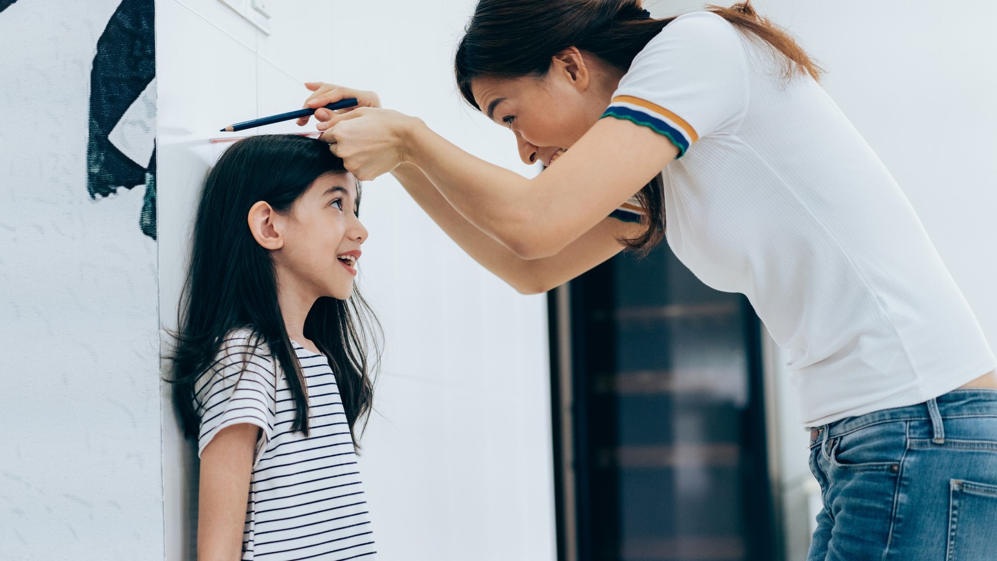 Woman measuring a child's height at home.