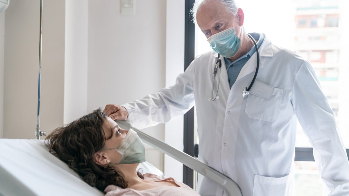 Photo of a breast cancer patient in a hospital bed talking to her doctor