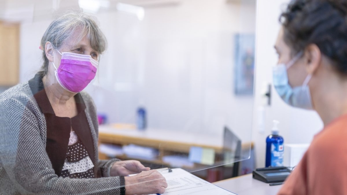 a receptionist helping patient fill out a form at medical clinic