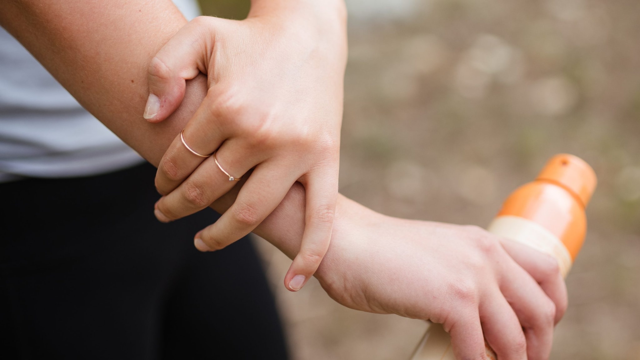 Woman applying insect repellant on her arm.