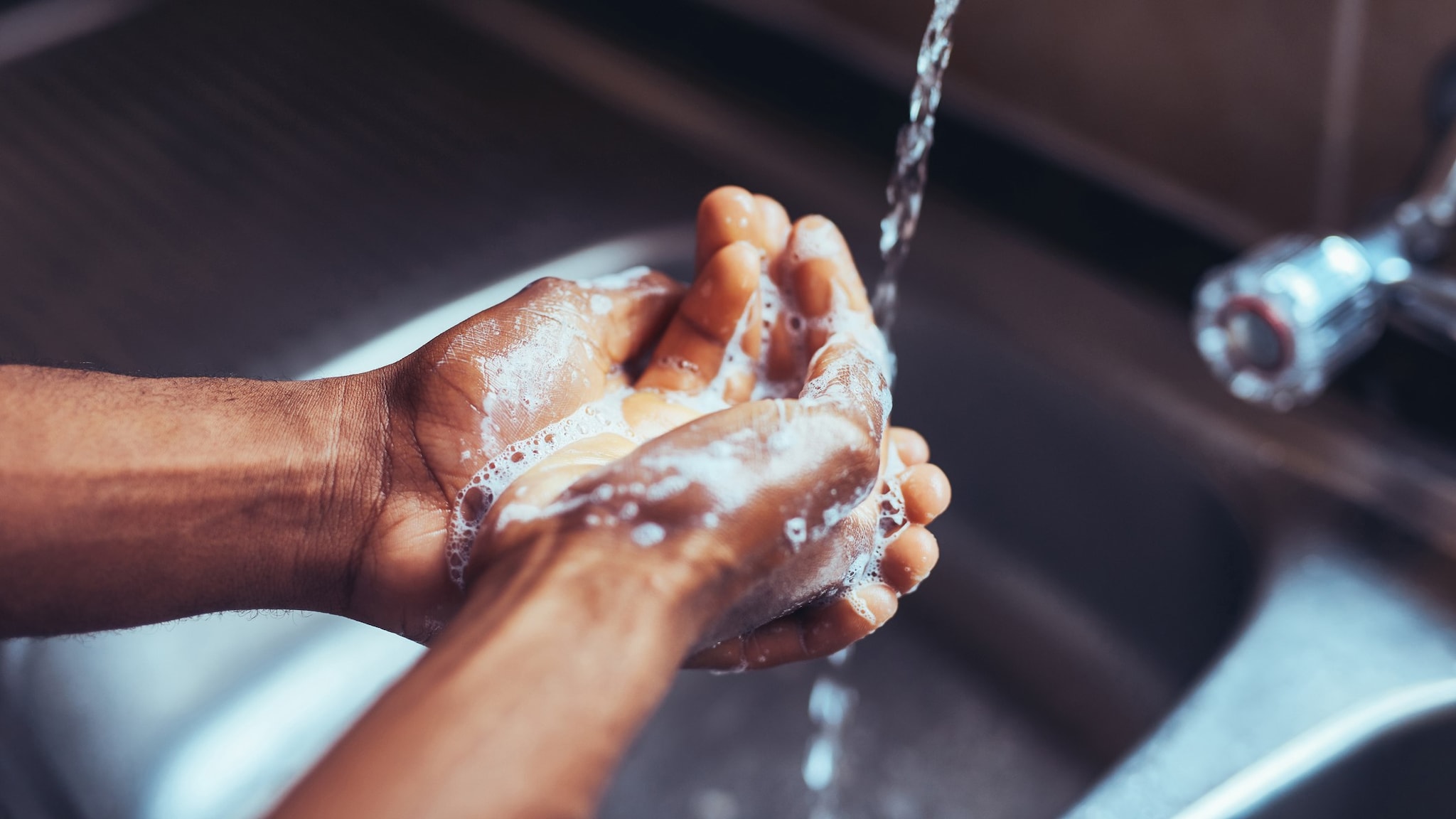 A person washing their hands in the sink with soap and water.