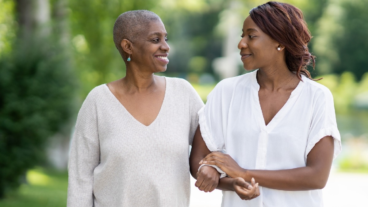 Foto de una sobreviviente de cáncer y su hija adulta caminando afuera