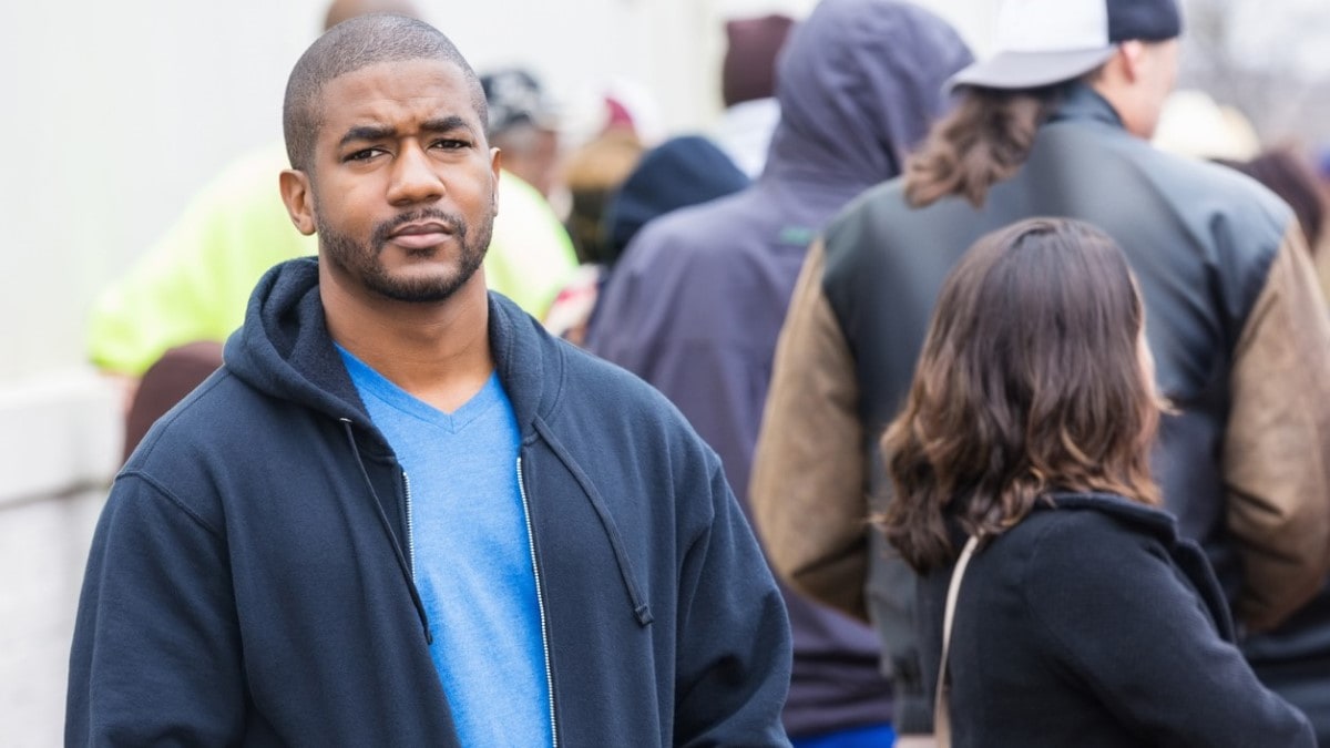 An African American man standing outside on a crowded city sidewalk