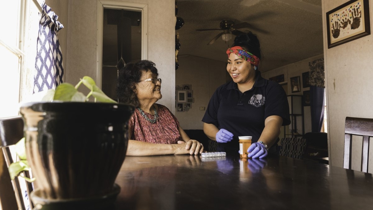 A community health worker helps a Navajo woman with her medication