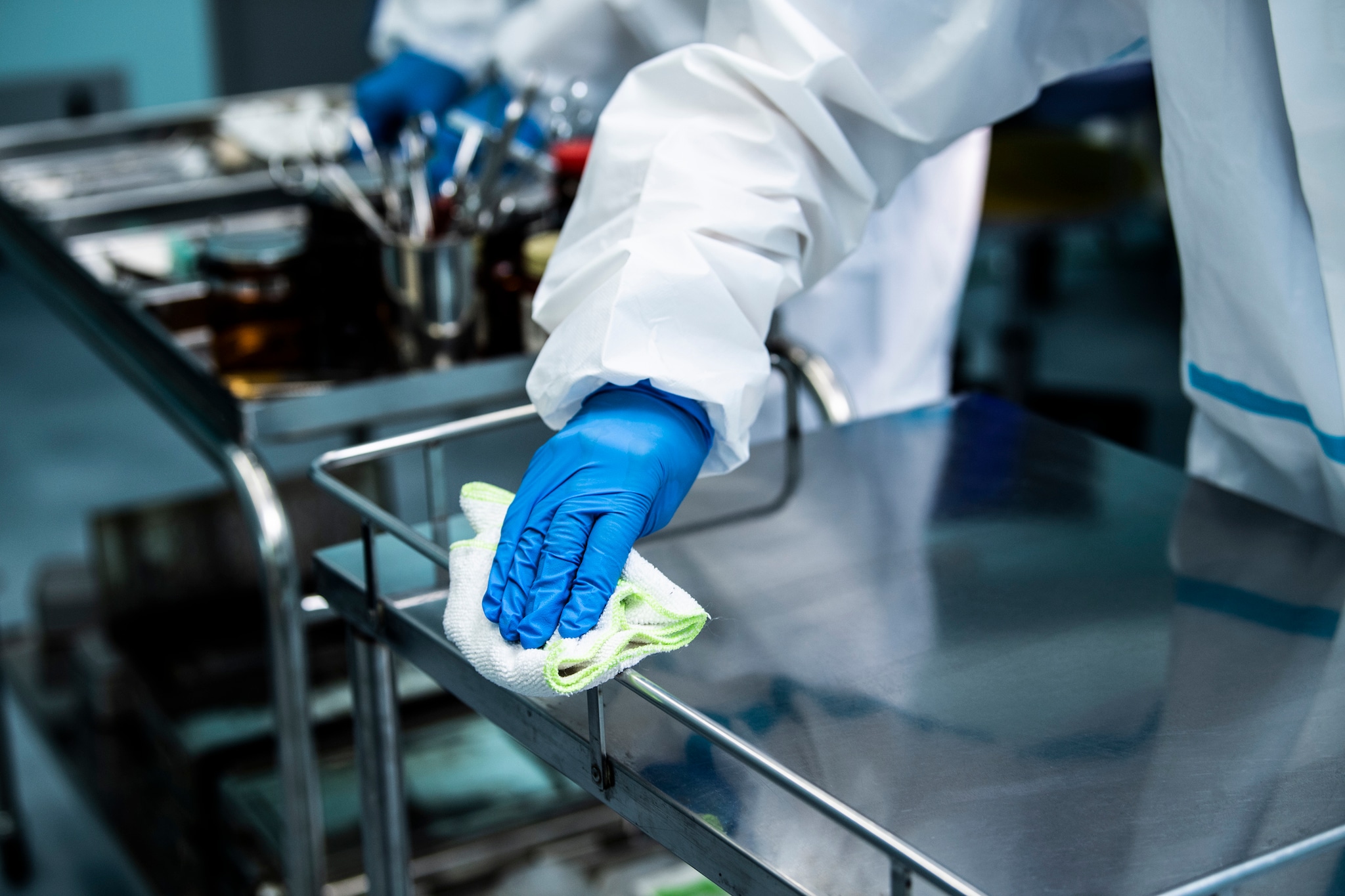 Hospital worker cleaning a cart.