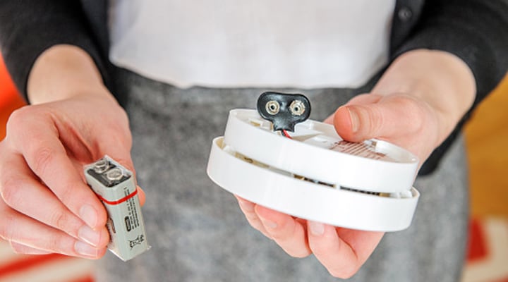 Hands holding 9 volt battery and carbon monoxide detector