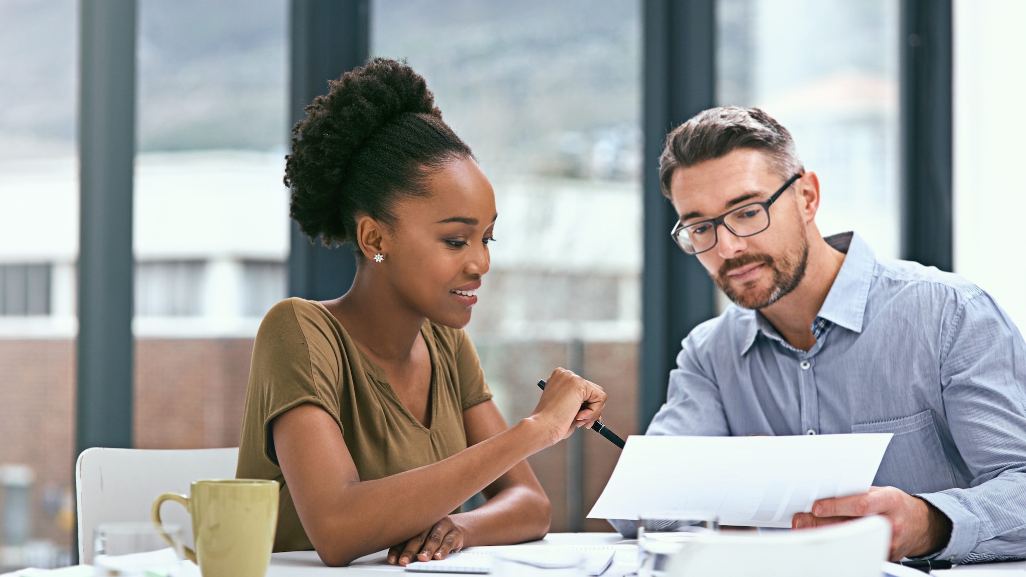 Two co-workers discussing reports at a table.