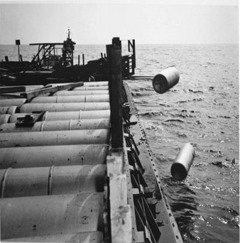 An image of bulk chemical containers being dumped in the sea from a ship.