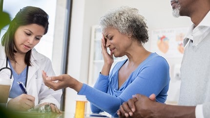 Woman at the doctor's office holding her head in pain