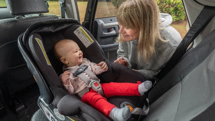 Woman next to baby strapped into rear-facing car seat