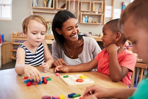 Maestra sonriente trabajando con tres niños pequeños