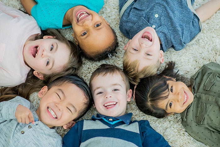 Kids laying on floor in circle with heads touching