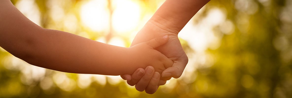 An adult hand holding a child's hand