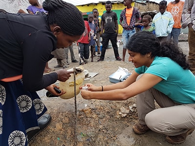 CDC worker and a woman take a water sample