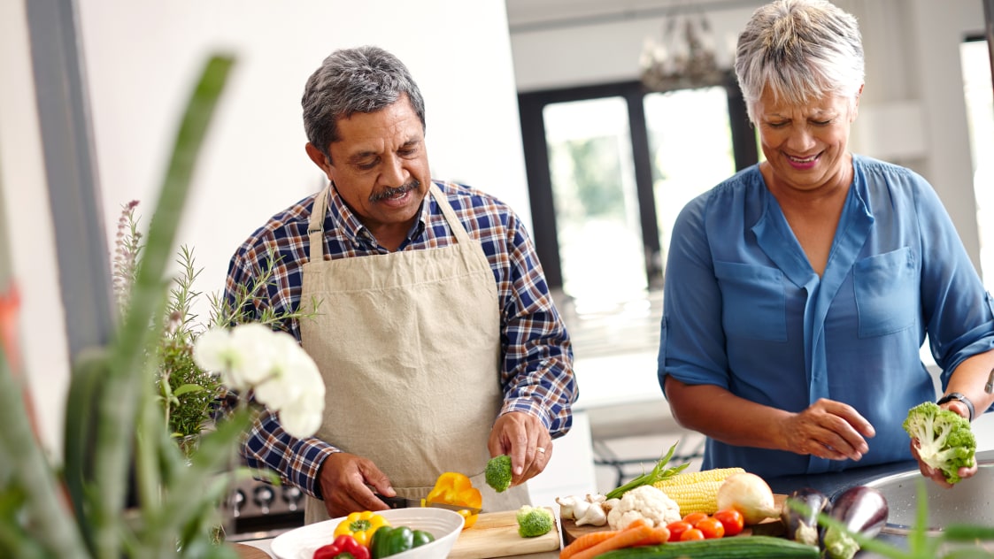 Pareja de mediana edad cortando verduras