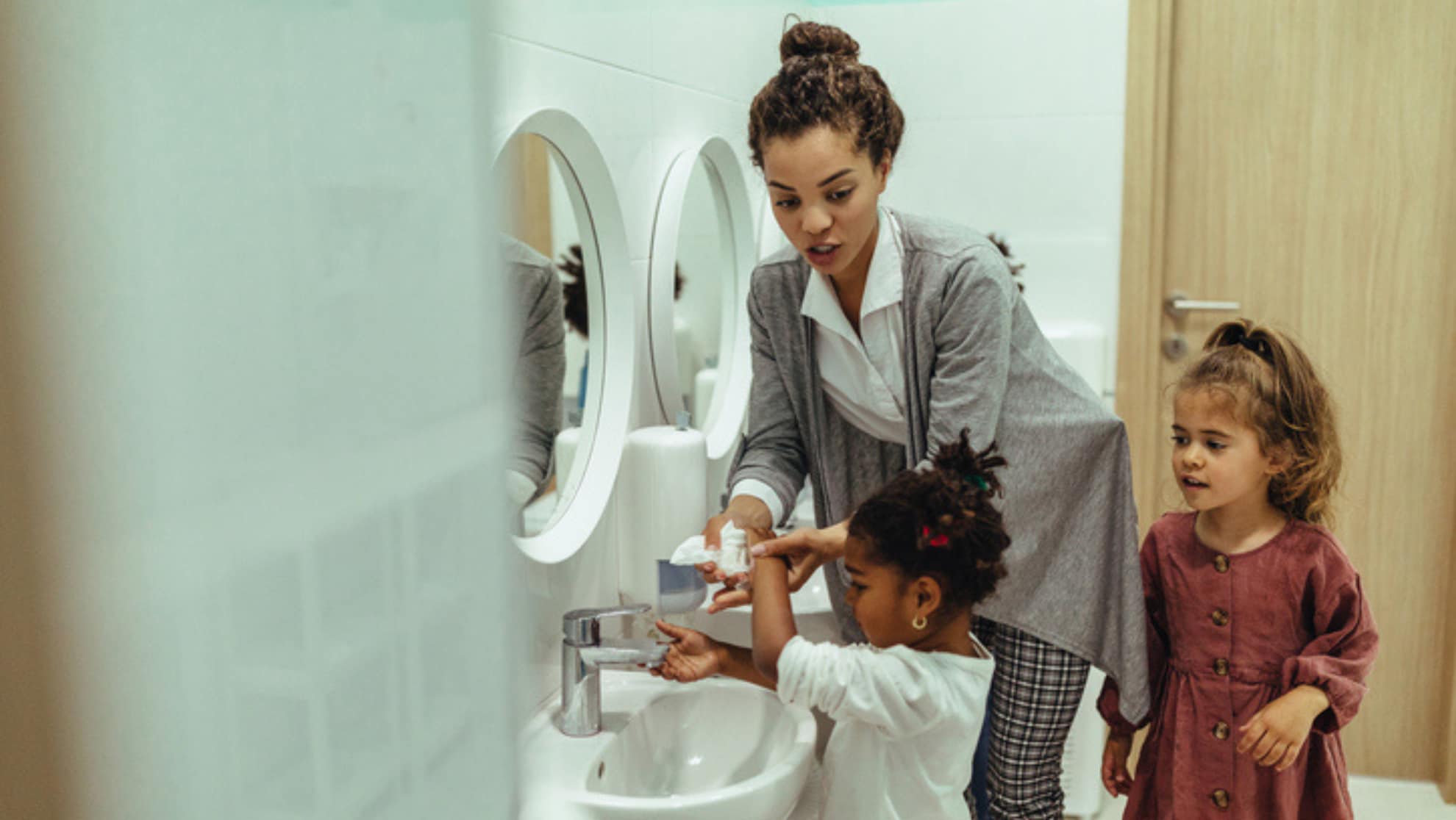 teacher helping child wash their hands