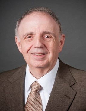 Dr. Penella's headshot. He is wearing a brown suit with a white shirt and brown striped tie.