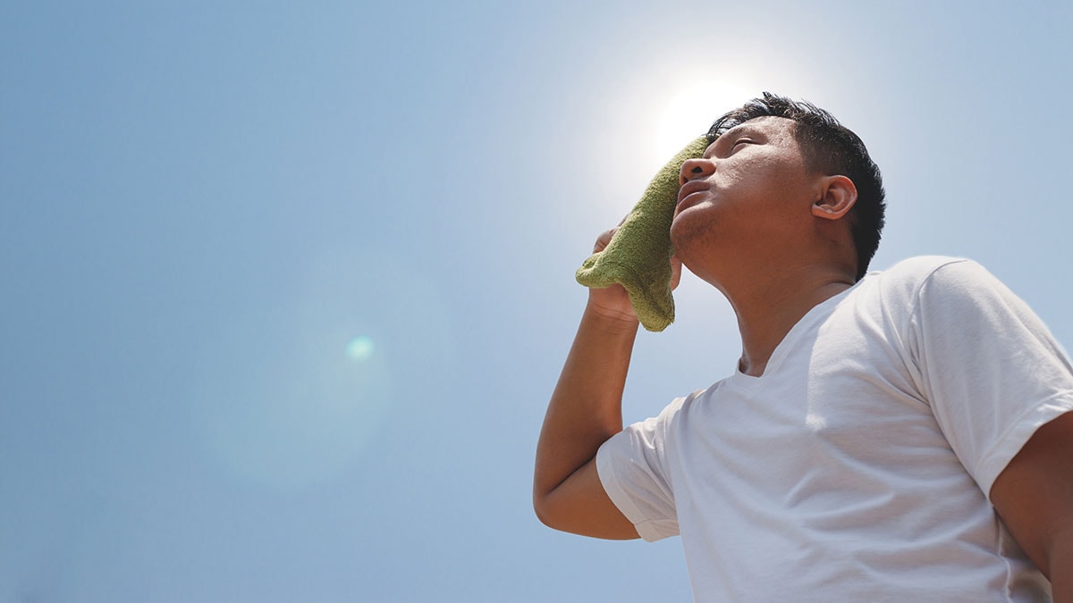 Young man hot in sun and wiping face with towel