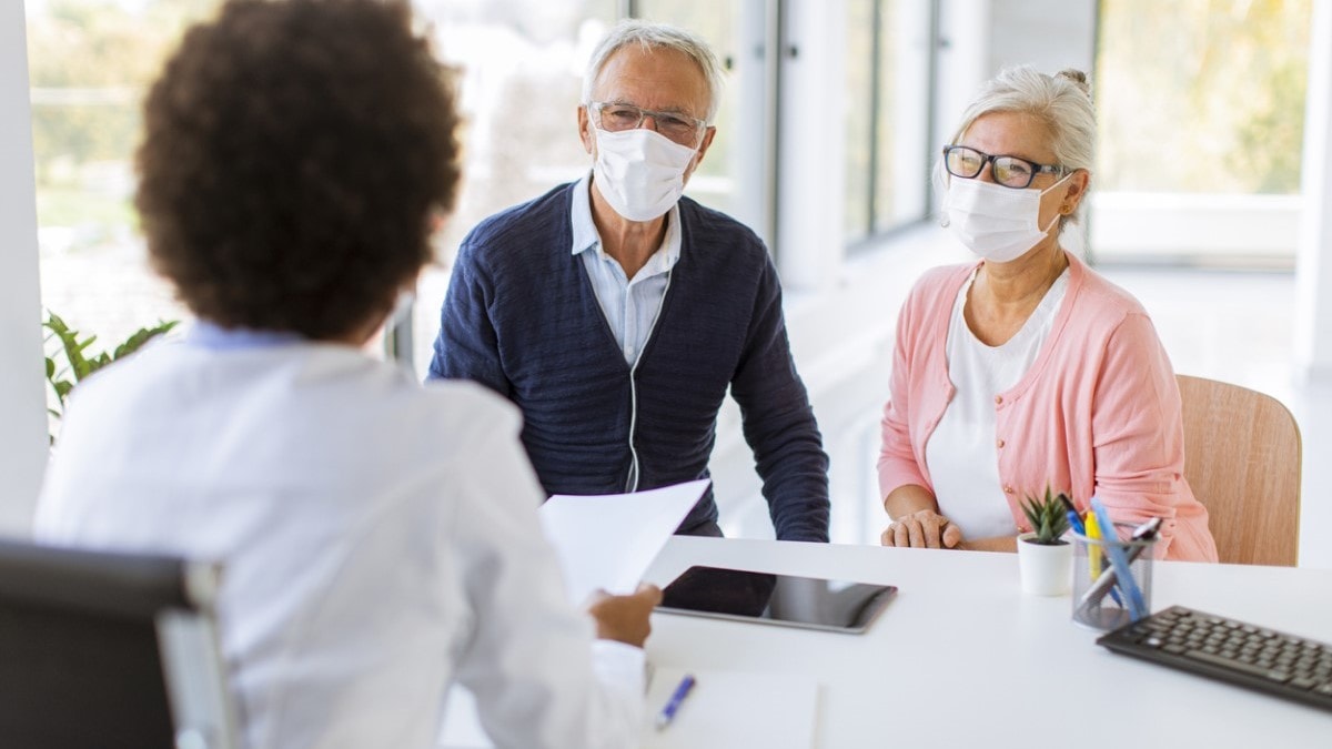 Un paciente y su esposa hablando con su médico