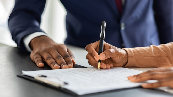 Two people writing on a pad of paper on a clipboard