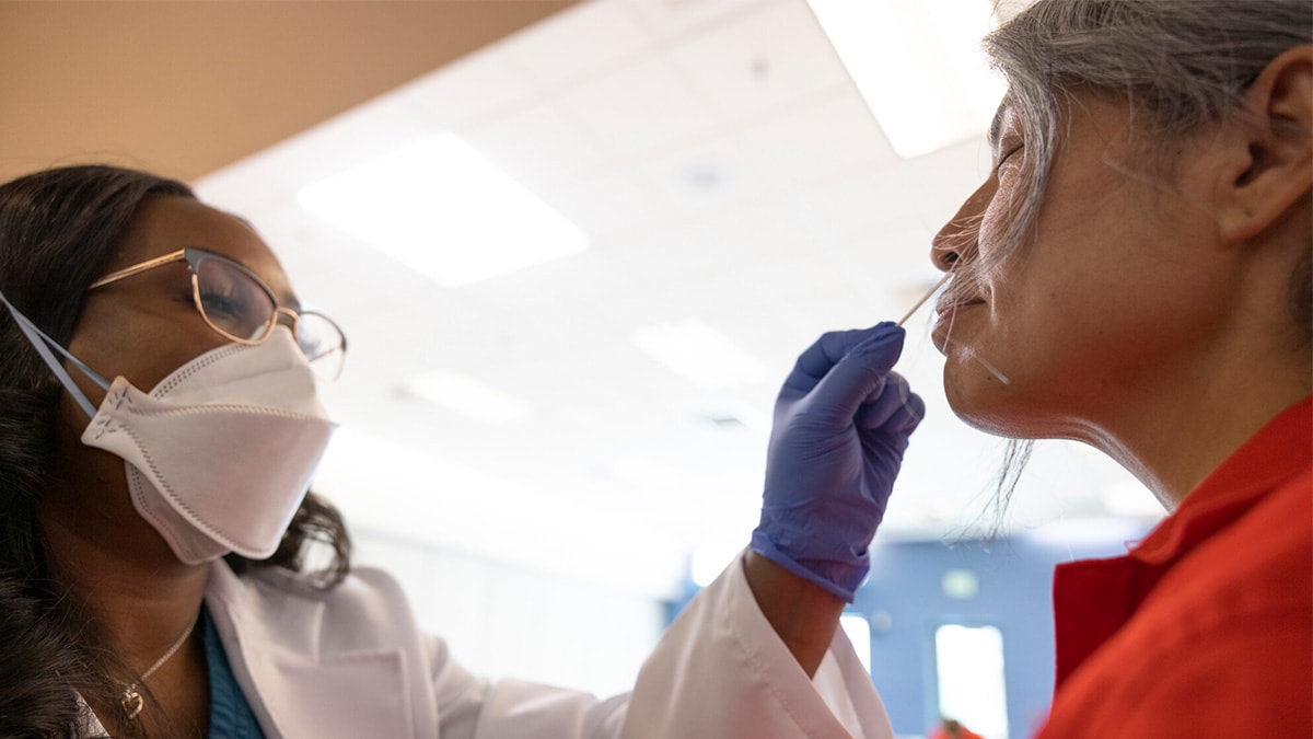 A female doctor performs a nasal swab on a female incarcerated patient during a medical examination.