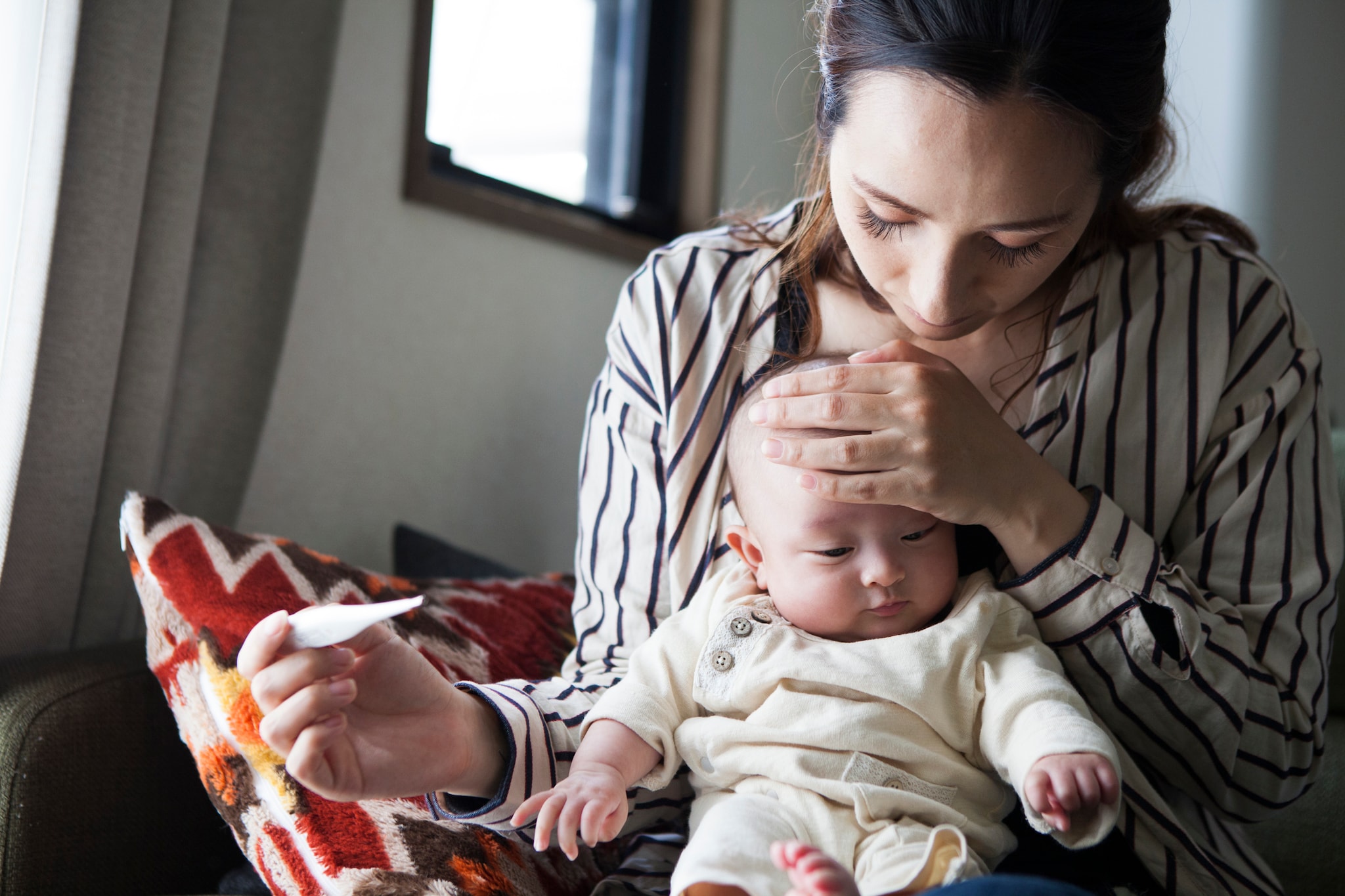 Woman holding baby and taking the child's temperature