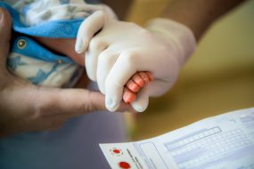 Image of a nurse and parent performing newborn screening using paper instead of digital means.