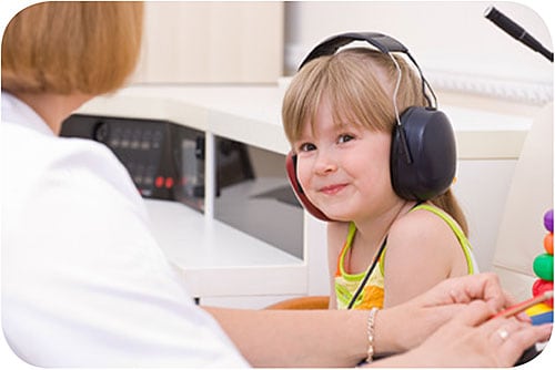 Niña pequeña a la que una médica le está haciendo pruebas auditivas.