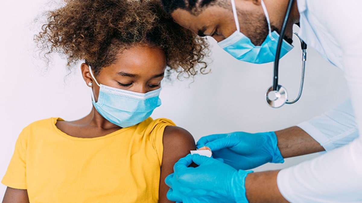 Healthcare provider applying a bandage to a child's arm.